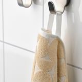 Beige towel with textured pattern hangs on silver hook, soft and absorbent.
