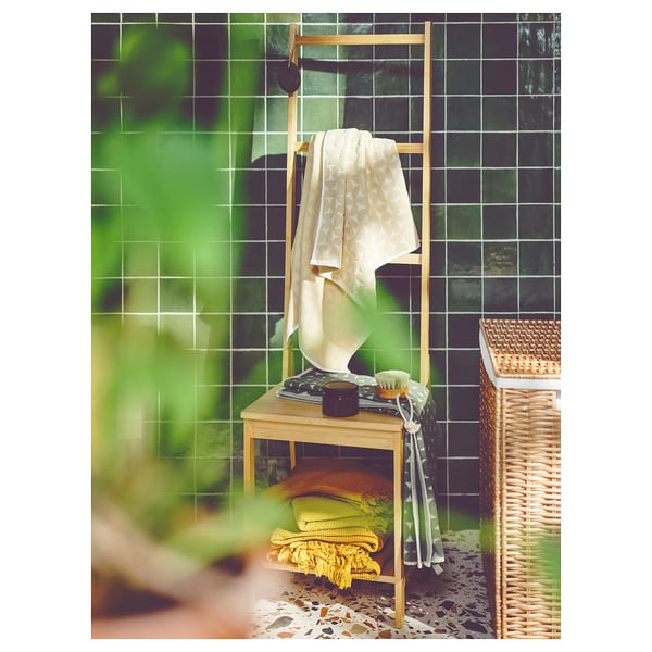 Beige ÄNGSNEJLIKA towel on wooden rack, jacquard pattern, colorful towels below.