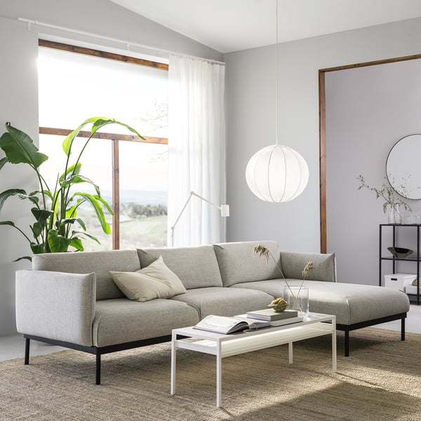 Modern living room with ÄPPLARYD gray sofa, white coffee table, large plant, pendant light, and natural light from windows.