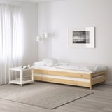 Modern bedroom with ÅFJÄLL white mattress on simple wooden bed, small white table, gray rug, and wall art.