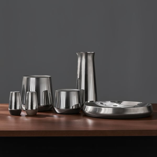Stainless steel carafe set with cups and tray on table. Sleek and modern design for cold drinks.