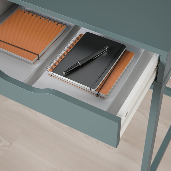 Open desk drawer with notebook, pen, and notepad; showcasing ALEXs cable management feature.