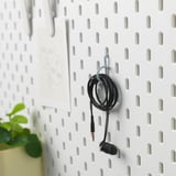 A pegboard mounts earphones with ALFORSIT cable ties, utilizing hooks for organized storage.