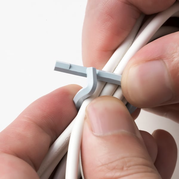 Hand holding white cables tightened by gray ALFORSIT cable tie, showcasing its securing function.