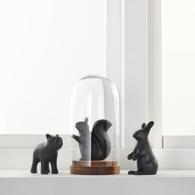 Three black ceramic animals displayed under a glass dome on a white shelf.