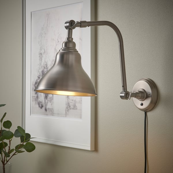Wall-mounted adjustable lamp with a brushed finish, emitting light from a globe.