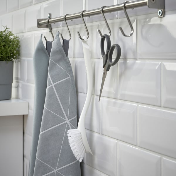 Metal rack with hooks holding kitchen tools: cloth, brush, scissors.