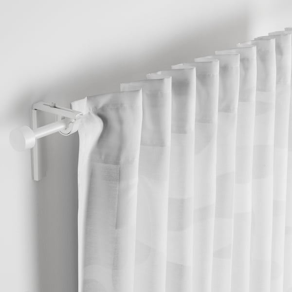 Curtains with geometric pattern, partially drawn, filtering light.