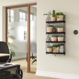 APOTEKARE wall shelf holds beige potted plants in black metal racks near black office chair.
