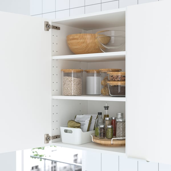 White cabinet with shelves holding jars, containers, and a wooden bowl, keeping kitchen items organized.