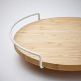 Round bamboo lazy susan with white metal handle, smooth surface, high edge, and clean design.