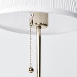 A modern lamp with a textured white shade, metallic finish, hanging pull chain.