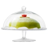 Clear glass cake stand with dome lid displays green cake, keeps contents fresh and protected.