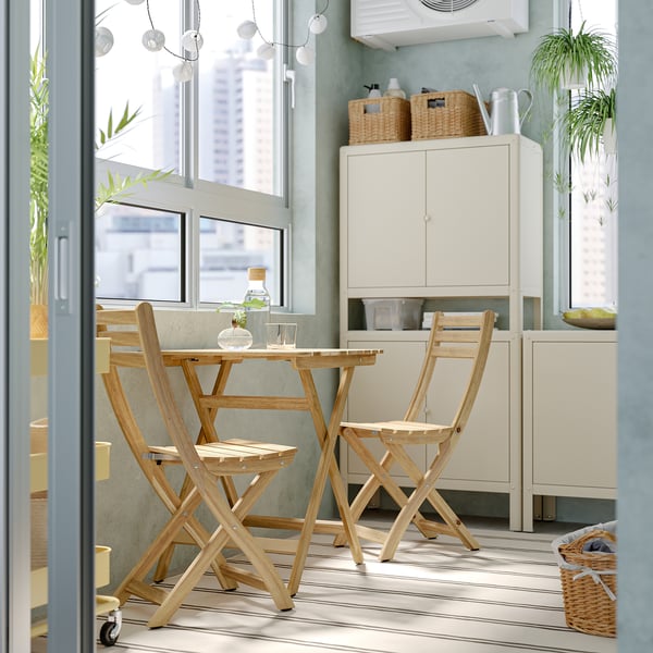 Bright room with ASKHOLMEN wooden table & chairs. Light wood, near window, with cabinet and plants. Cozy, compact setup.