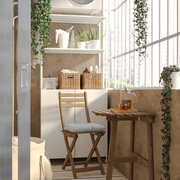 Bright kitchen nook with wooden stool & table, white decor, & hanging plants.