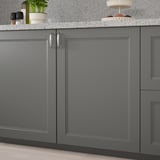 Dark grey kitchen cabinets with a sleek, modern design. Handles are on the left side, and theres a countertop with items like a plant and bowls on it.