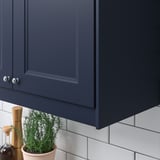 Gray kitchen cabinet with plant and salt shaker, hidden lighting.