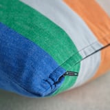 Close-up of multicolored striped cushion cover, showcasing zipper detail. Bright, modern design with blue, green, gray, and orange stripes.