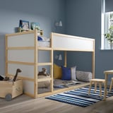 Childs room with wooden bunk bed, stuffed toys, striped pillows, blue walls, and a rug. BÄNKKAMRAT pads are placed underneath for comfort and safety.