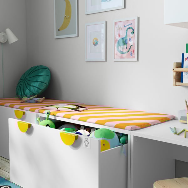 Childs room with colorful bedding & toys. Art on walls, desk with books & lamp.
