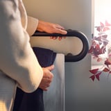 An elderly person holding a dark grey BÄSINGEN towel rail, designed with rounded edges for safety.