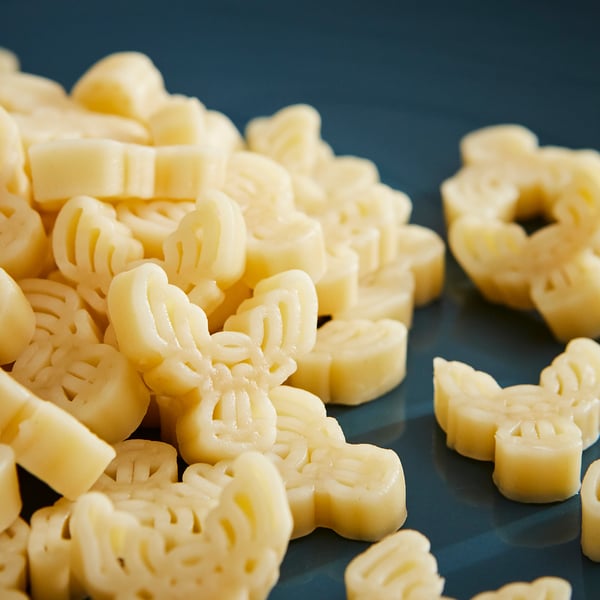 Pile of yellow moose-shaped pasta on dark surface. Höchst 150 characters.