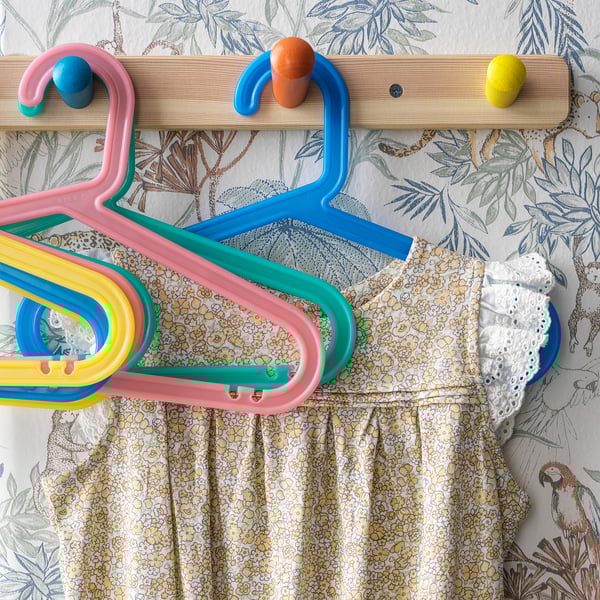 Colorful childs clothes hangers on decorative wallpaper.