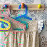 Colorful childs clothes hangers on decorative wallpaper.