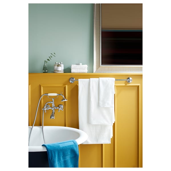 Yellow-green bathroom, chrome shower, blue/white towels, glass jar.