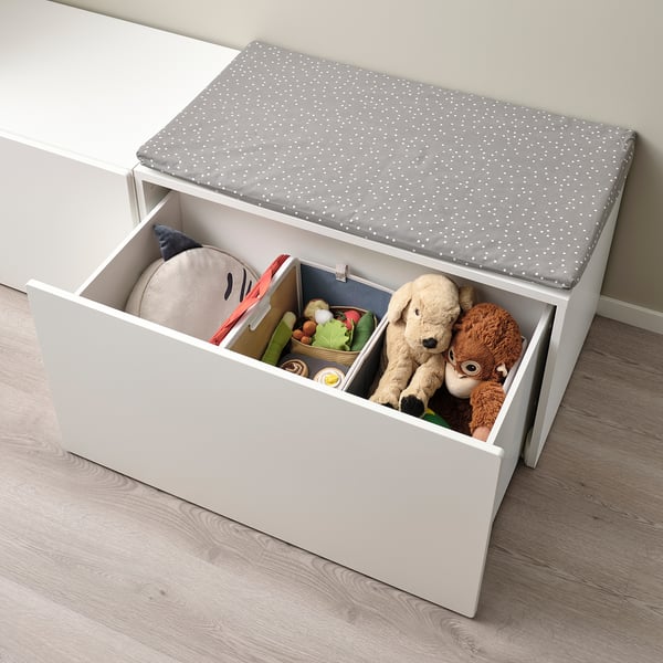 White toy box with grey dotted cushion. Stores plush toys, books, and stuffed animals. Foldable for space-saving.