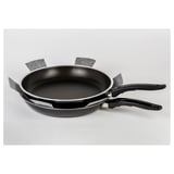 Stacked black frying pans with protective gray fabric strips, displayed on a light surface.