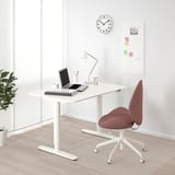 White BEKANT standing desk with red chair, adjustable height, spacious surface.