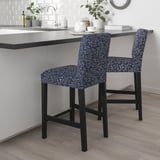 A pair of black and floral-patterned BERGMUND bar stools sit against a gray kitchen island, contrasting the white background and adding a cozy touch.