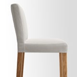 Modern bar stool with plush, patterned seat and light wooden legs, offering comfort and style.