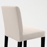 A beige upholstered chair with black legs, designed for comfort and style, shown against a plain wall.