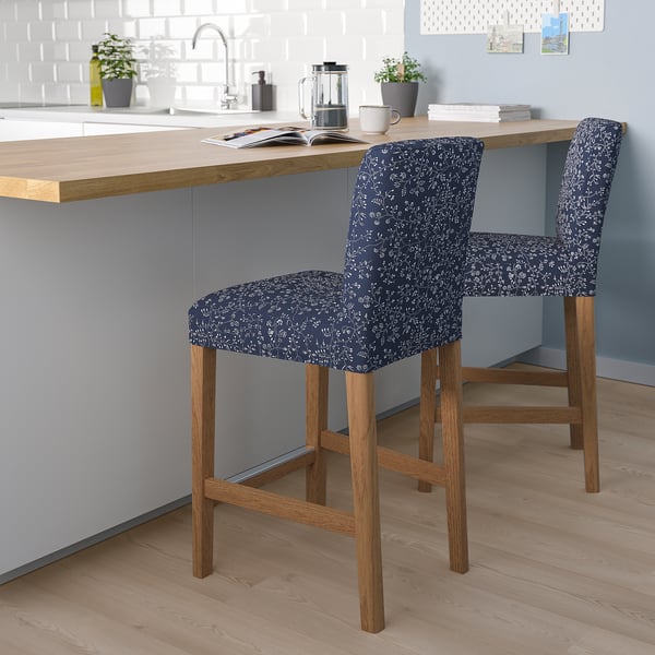 Two blue floral-patterned bar stools with wooden legs at a kitchen counter. Decorative and comfortable seating for a modern kitchen.