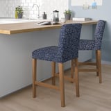 Two blue floral-patterned bar stools with wooden legs at a kitchen counter. Decorative and comfortable seating for a modern kitchen.