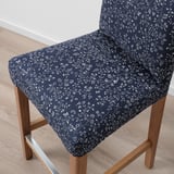 A stylish, dark-colored barstool with intricate white floral patterns, featuring a cushioned seat and backrest for comfort.