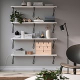 Minimalist shelf with white BERGSHULT shelves, books, vases, plants, lamp, and chair.