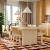Modern dining room with large light wood table, six chairs, rug, and hanging lamps.
