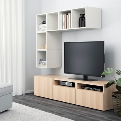 Modern living room with built-in wall storage and light wood tv stand. Flat-screen tv sits on stand with open shelves and drawers.