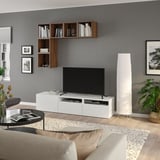 Modern living room with BESTÅ white tv stand, shelves, books, decorations, beige sofa, black coffee table, and white floor lamp.