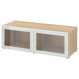 An ikea BESTÅ storage unit in oak effect and white with glass doors. Its rectangular with clean lines and sleek design.