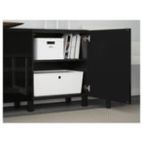Black wooden cabinet with glass top, two drawers, and shelves, organized with white storage containers.