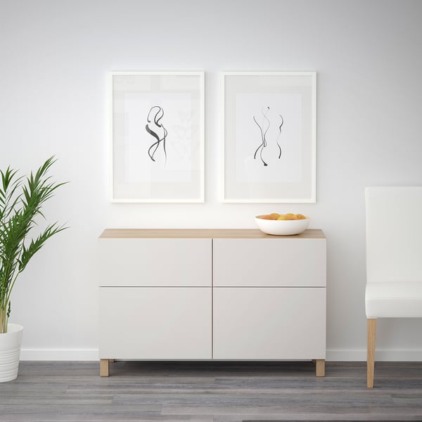 Minimalist white sideboard with adjustable shelves, two drawers, and push-open mechanism. Top displays bowl, art, and plant.