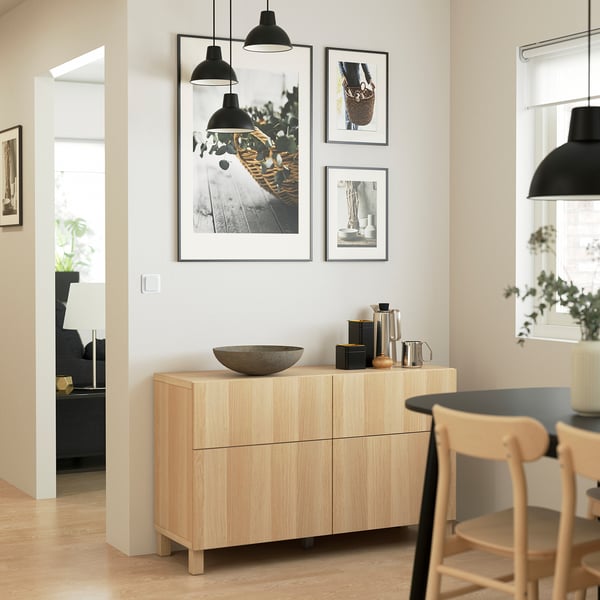 Modern living room with BESTÅ sideboard, artwork, lights, and dining area.