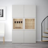 White BESTÅ cabinet, with glass doors showcasing wine glasses and bottles inside. Display and storage combo with adjustable shelves.