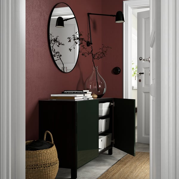 Open sideboard with adjustable shelves shows organized storage. Vase and branches decorate top. Dark walls and minimalist design.
