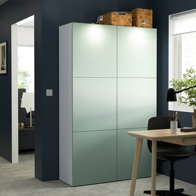 Tall light blue-green BESTÅ cabinet with 4 doors, shelves, & baskets in minimalist room.