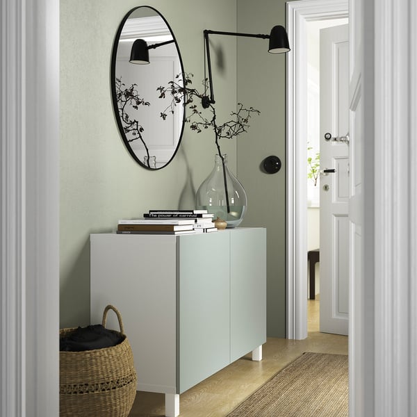 Modern green BESTÅ with mirror, lamps, and blankets.